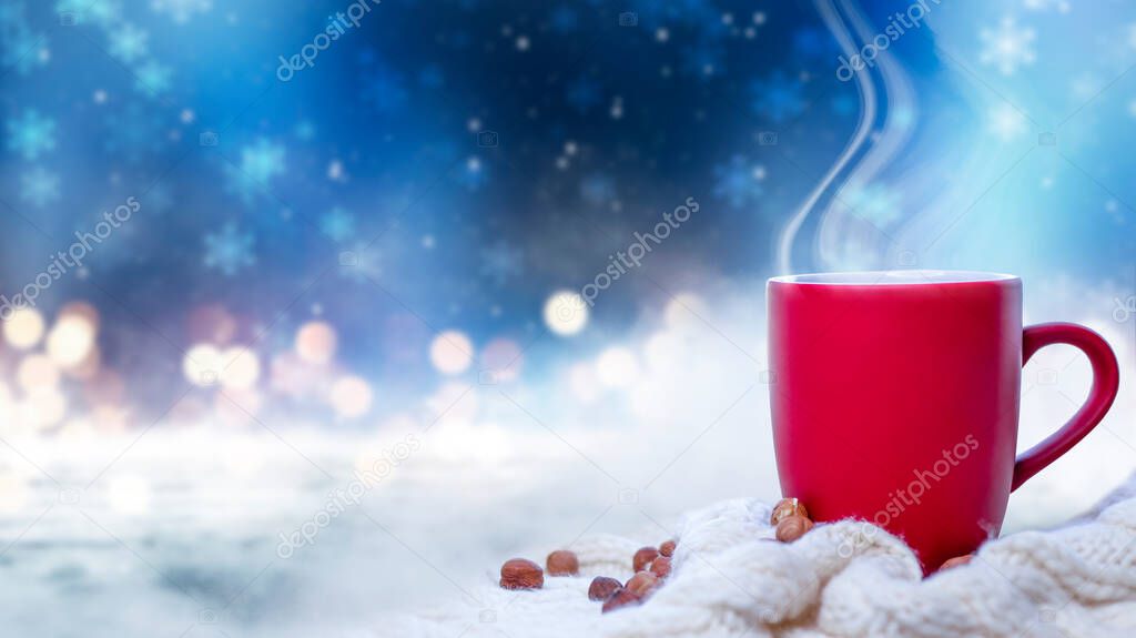 Red cup with coffee, tea on a snowy background, winter forest. A red cup against the background of a winter forest landscape on a soft, cozy scarf. Coffee, tea in the mountains.