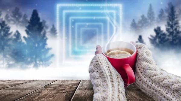 Red cup with coffee, tea in female hands on a snowy background, winter forest. A red cup in hands against the background of a winter forest landscape on soft, knitted sleeves. Coffee, tea on a wooden