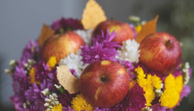 Bir buket çiçek ve elma. Sonbahar parlak arka plan, elmalar, koza, kuru yapraklar. Eylül Kasım. Sarı ve turuncu renklerle mevsimlik sonbahar arkaplanı.