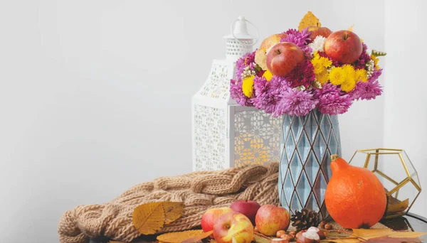 Autumn bouquet of flowers and apples. Autumn bright background with apples, chrysontema, dry leaves. September October November. Seasonal autumn background with yellow and orange colors.