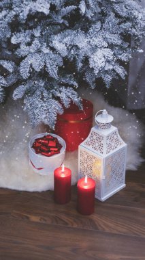 Yeni yıl iç kısımları, kar ağacı, gece feneri ve mumlar, hediyeler. Noel ve yeni yılın büyülü atmosferi. Oyuncak ayı Noel Baba şapkasıyla Noel ağacının yanındaki sandalyede oturuyor..