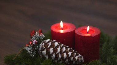 Köknar dallı kırmızı mumlar ve oyuncak çam kozalağı. Karanlık Noel ve yeni yıl geçmişi. Kırmızı mumlar, yeşil ladin dalları, kırmızı çilekler..