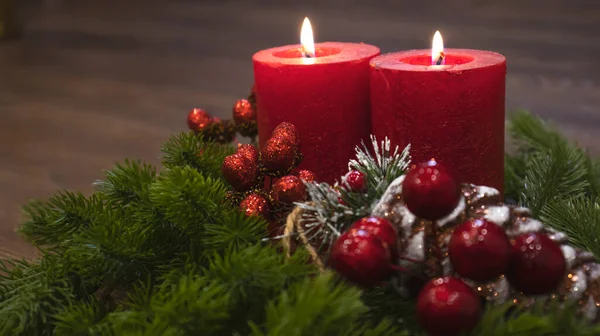 Red candles with fir branches and a toy pine cone. Dark Christmas and New Year background. Red candles, green spruce branches, red berries.