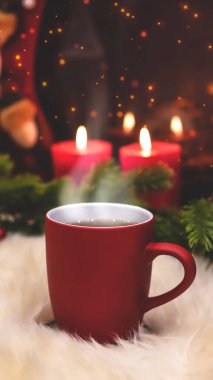 Yeni yılın arka planında kırmızı bardak, şömine, mumlar, Noel ağacı çelengi. Şöminenin yanında sıcak bir kış akşamı. Yeni yıl ve Noel şenlik geçmişi.