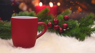 Yeni yılın arka planında kırmızı bardak, şömine, mumlar, Noel ağacı çelengi. Şöminenin yanında sıcak bir kış akşamı. Yeni yıl ve Noel şenlik geçmişi.