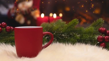 Yeni yılın arka planında kırmızı bardak, şömine, mumlar, Noel ağacı çelengi. Şöminenin yanında sıcak bir kış akşamı. Yeni yıl ve Noel şenlik geçmişi.