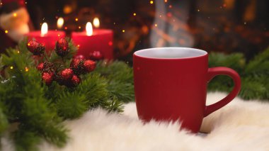 Yeni yılın arka planında kırmızı bardak, şömine, mumlar, Noel ağacı çelengi. Şöminenin yanında sıcak bir kış akşamı. Yeni yıl ve Noel şenlik geçmişi.