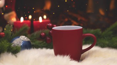 Yeni yılın arka planında kırmızı bardak, şömine, mumlar, Noel ağacı çelengi. Şöminenin yanında sıcak bir kış akşamı. Yeni yıl ve Noel şenlik geçmişi.
