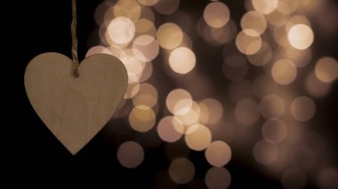 Bulanık bir bokeh arka planda kalp şeklinde ahşap bir Noel oyuncağı. Yakın plan, bulanık arkaplan. Şenlikli yeni yıl geçmişi. Kartpostal, gece görüşü..