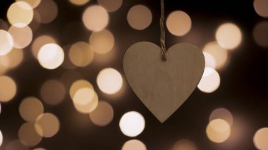 Bulanık bir bokeh arka planda kalp şeklinde ahşap bir Noel oyuncağı. Yakın plan, bulanık arkaplan. Şenlikli yeni yıl geçmişi. Kartpostal, gece görüşü..