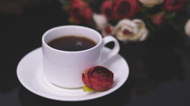 Bir fincan kahve ve çiçek. Romantik bir geceye davetiye. Kalpler bokeh, kırmızı ışık etkisi. Kartpostallar için klasik arkaplan.