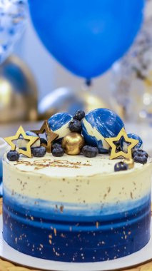 Arka planda balonlar ve ışıltılarla el yapımı bir doğum günü pastası. Cheesecake keki, mavi ve altın aksanlı. Kartpostal, tatil, doğum günü, yıldönümü, 18 yıl. 