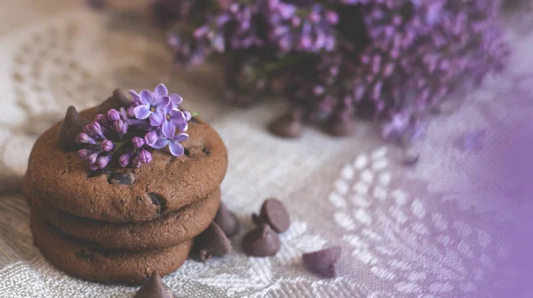 Decorative composition with a Bouquet of lilacs in a light kitchen interior. Clay cup of tea and chocolate cake. A bouquet of lilacs in a vase. Spring floral background with lilacs in the interior.