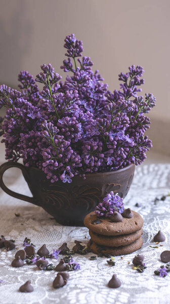 Декоративная композиция с букетом сирени в светлом интерьере кухни. Чашка чая и шоколадный торт. Букет сирени в вазе. Весенний цветочный фон с сиренью в интерьере. 