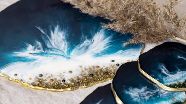 Cup holder, epoxy resin tray, marine-style stone cut. Blue stains of paint, gold trim. Subject for table setting. Gloss, reflection. The effect of the sea. Blurred background.  clipart