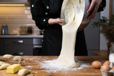 Mutfaktaki ahşap masada hamur yoğuran genç ve güzel bir kadın. Ev hanımı hobileri konsepti.