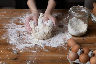 Mutfaktaki ahşap masada hamur yoğuran genç ve güzel bir kadın. Ev hanımı hobileri konsepti.
