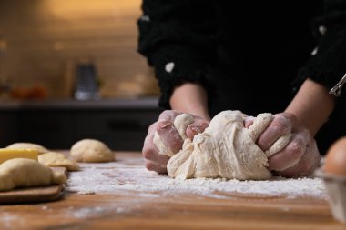 Mutfaktaki ahşap masada hamur yoğuran genç ve güzel bir kadın. Ev hanımı hobileri konsepti.