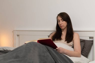 Yatmadan önce kitap okuyan güzel bir kadının yan görüntüsü. Sağlıklı yaşam tarzı.