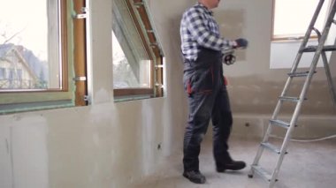Yeni inşa edilmiş çatı katında yeni pvc pencereler için pencere pervazı ölçümleri yapan tamirci