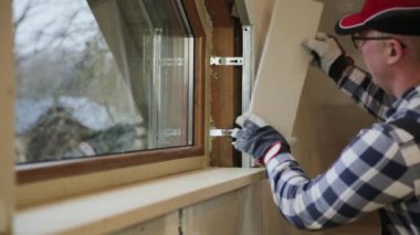 ev geliştirme ustası yeni inşa tavan arasına pencere kurmak için levye ve lazer dengeleyici kullanılıyor