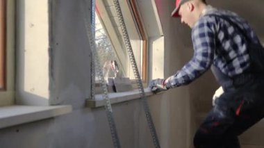 ev geliştirme ustası yeni inşa tavan arasına pencere kurmak için levye ve lazer dengeleyici kullanılıyor