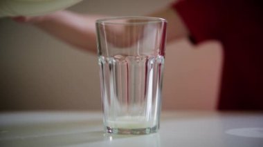 Kırmızı elbiseli kadın bardağa süt döküyor. Laktoz duyarlılığı, inek sütü, sağlık konsepti