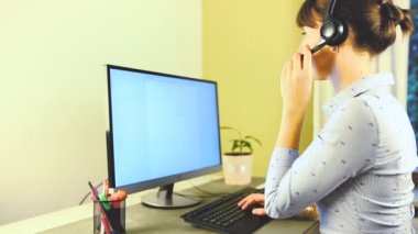 Gülümseyen kadın müşteri hizmetleri yöneticisi ofiste kulaklıkla konuşuyor. Yardım masası, bilişim destek konsepti