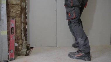 Adam tavan arası inşaatı için duvarlara alçı levha yerleştiriyor.