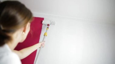 Ev tadilatı. Güzel bir kadın boya silindiriyle duvar boyuyor..