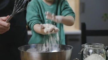 Bir çocuk ve anne, ahşap bir masada sıcak bir mutfakta hamur hazırlıyor. Aile hayatı ve hobi kavramı.
