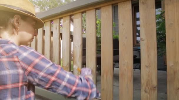 拿着画笔画木制阳台栏杆的女人 室外开枪 — 图库视频影像