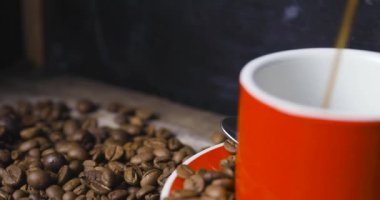 Kırmızı kahve fincanı ve koyu dokulu kahve çekirdekleri. Sabah taze enerji kavramı.