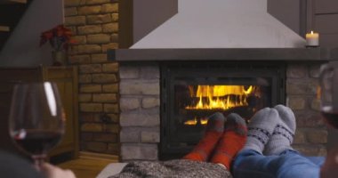 Birbirine aşık bir çift, şöminesi olan sıcak bir odada oturuyor. Kanepede bir kadeh şarapla. Aile ve aşk kavramı.