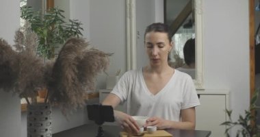 Güzel genç kadınlar online cilt bakımı kursuna gidiyor. Kil yüz maskesi karıştırmak ve akıllı telefonun önünde izleyicilere göstermek. Güzellik ve cilt bakımı.