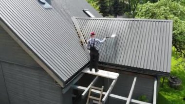 Çatıyı yüksek basınçla yıkayan becerikli bir adam.