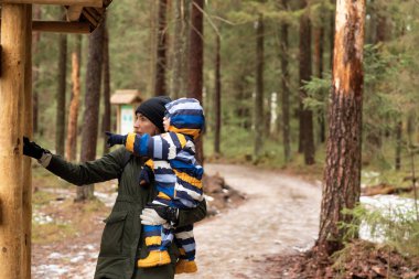 Genç bir anne ve çocuk ulusal bir park ormanında yürüyüş yapıyor. Anne, erkek erkeğe bilgi veriyor. Sağlıklı yaşam kavramı.