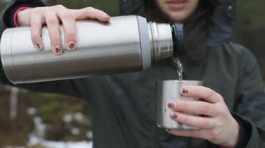 Soğuk bir yağmurda termostan fincana içecek dolduran genç ve güzel kadınlar. Sağlıklı yaşam ve yürüyüş.
