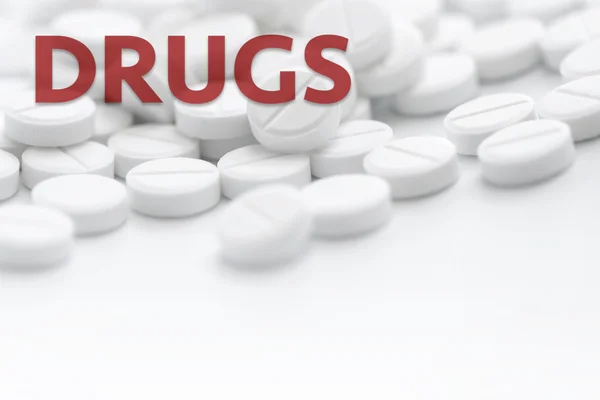 Haufen weißer Pillen in Nahaufnahme auf weißem Hintergrund mit Text dru — Stockfoto