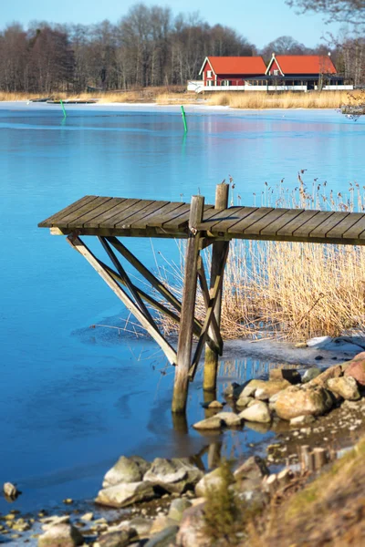 Pontile di legno all'inizio della primavera con ghiaccio sottile sull'acqua — Foto Stock