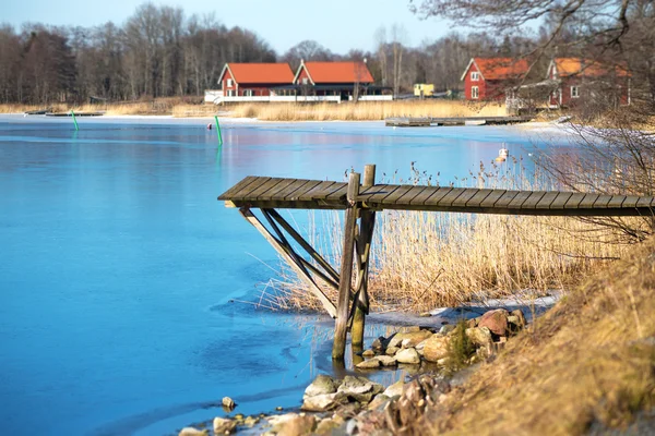 Dřevěné molo během časného jara s tenkým ledem na vodě. — Stock fotografie