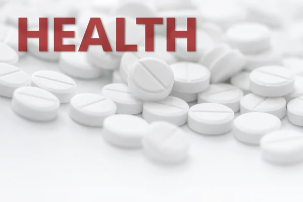 Weiße Tabletten in Nahaufnahme auf weißem Hintergrund mit Text Gesundheit in — Stockfoto