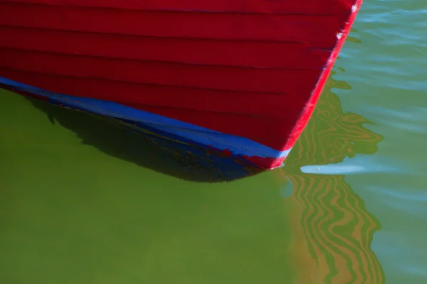 Arco de barco de pesca vermelho em close-up na água com reflexos no — Fotografia de Stock