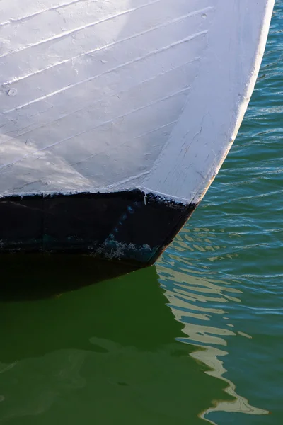 Рыбацкая лодка лук в крупном плавании в воде с отражениями в гре — стоковое фото