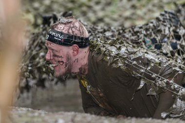 Tough Viking engel kuryalarında çamurlu ağ tuzağının altında sürünerek