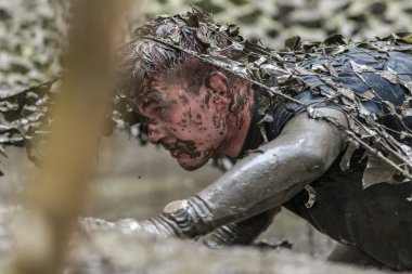 Tough Viking engel kuryalarında çamurlu ağ tuzağının altında sürünerek