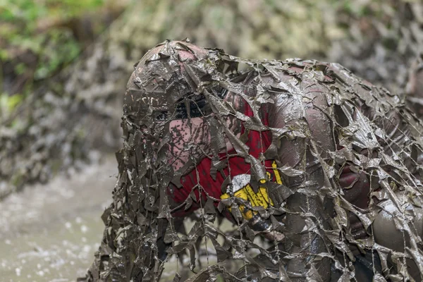 Rampant sous le piège à filet boueux dans le difficile parcours d'obstacles Viking — Photo