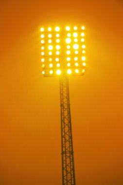 Floodlights on a high tower in yellow color clipart