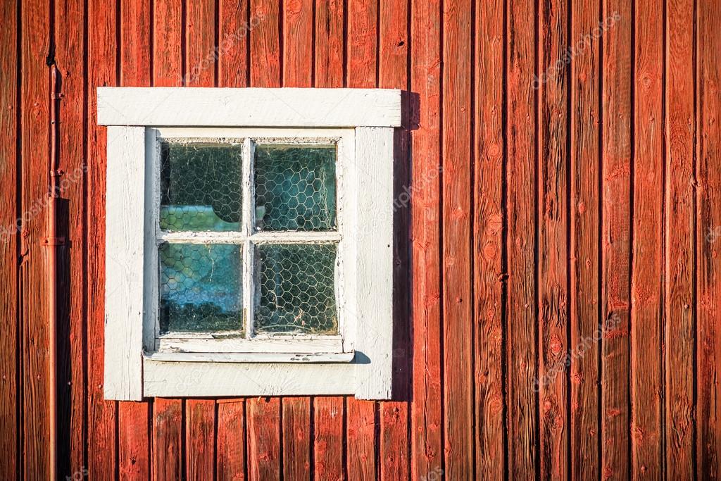 Square white window in old red wooden barn wall