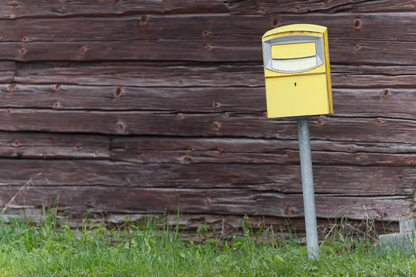 Traditional yellow postbox in front og a wooden wall — Stock Photo, Image